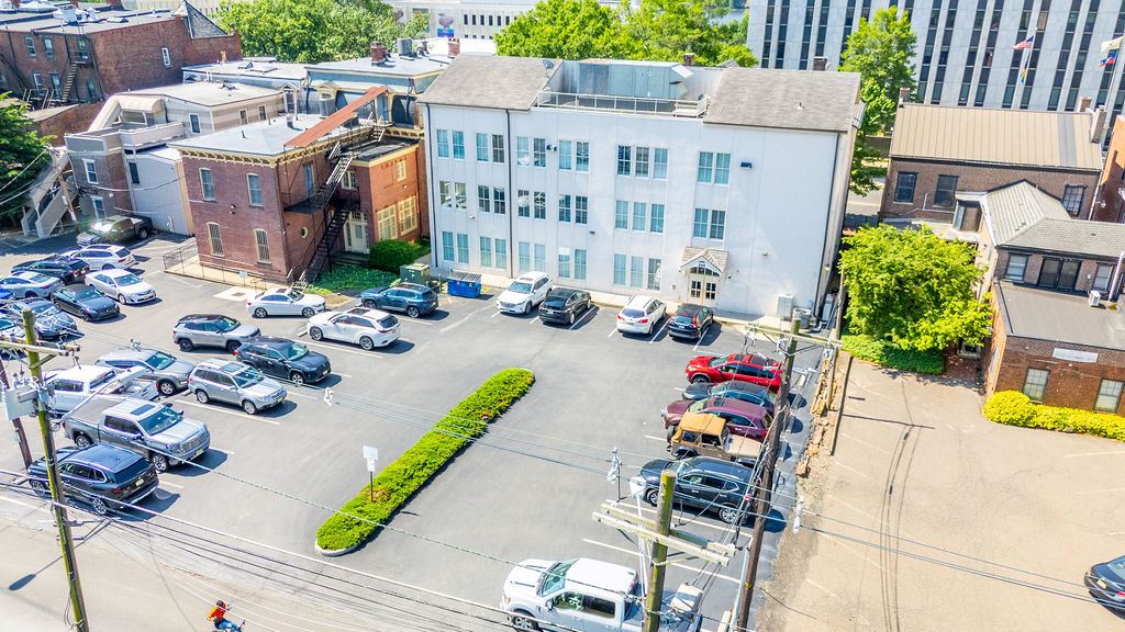 Aerial view of a parking lot with cars and the back of a white building